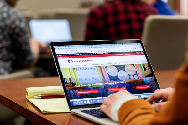 Student sitting at a table in the library working on a laptop computer