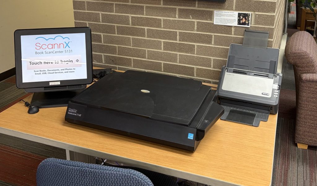 flat-bed book scanner on a table next to touchscreen monitor